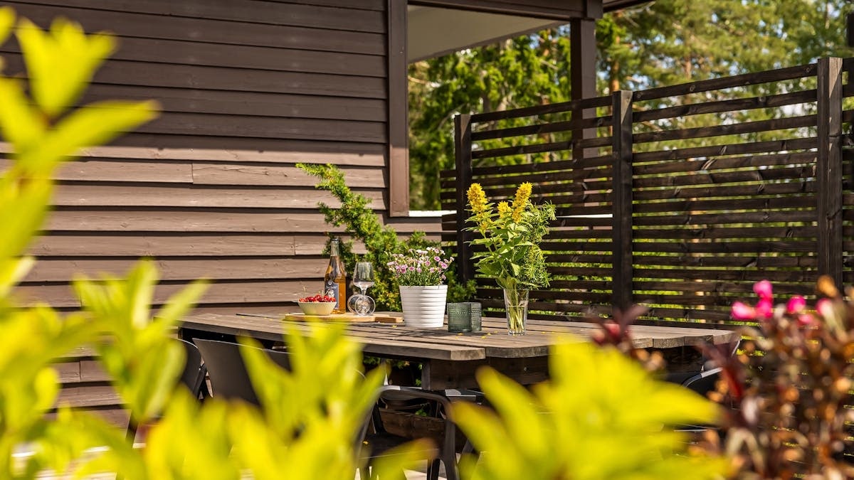 Outdoor patio with wooden table, chairs, and vibrant plants in summer.